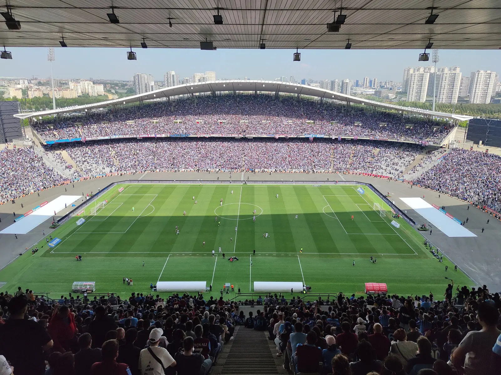 Football match in the Atatürk Olympic Stadium in Istanbul seen from the stands with city buildings beyond