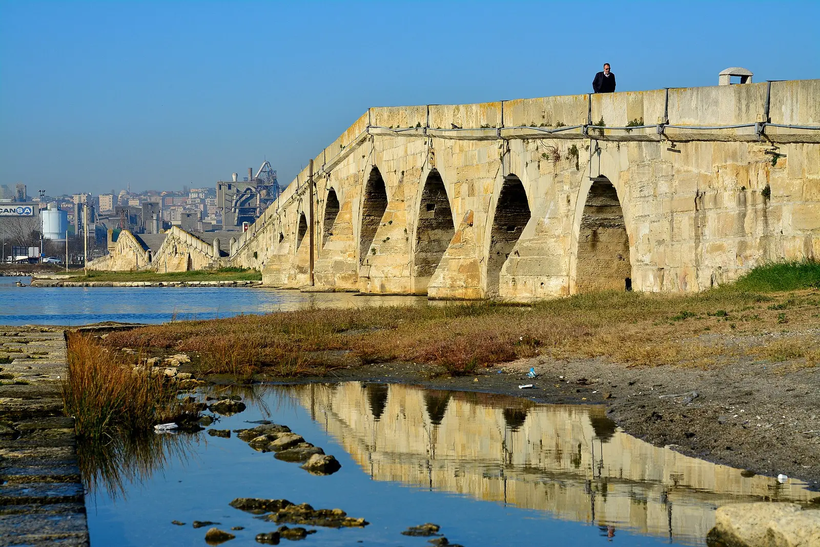 Stone arches of the Sultan Suleyman bridge at Buyukcekmece, Istanbul, reflected in the water