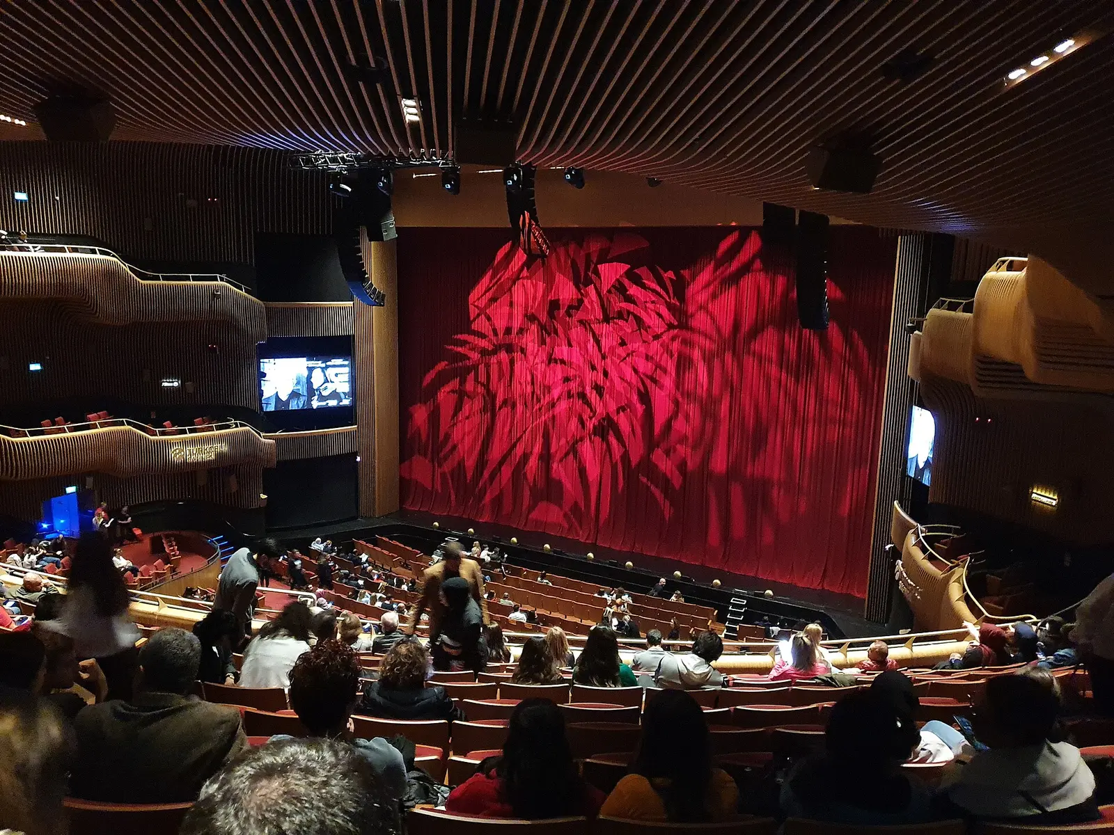Audience seated in the Turkcell Stage hall at Zorlu PSM facing a red stage curtain